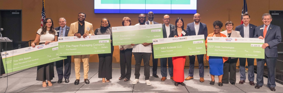 The finalists for the 2025 HCC Business Plan Competition pose for a photo while holding large green checks.